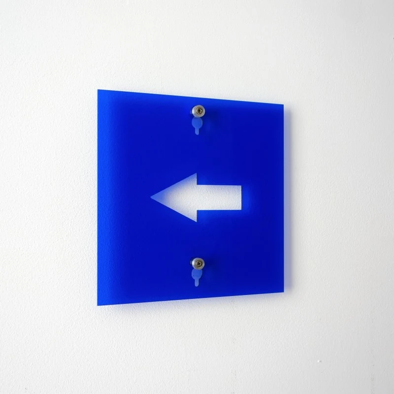 un panneau indicateur bleu avec une flèche à gauche.