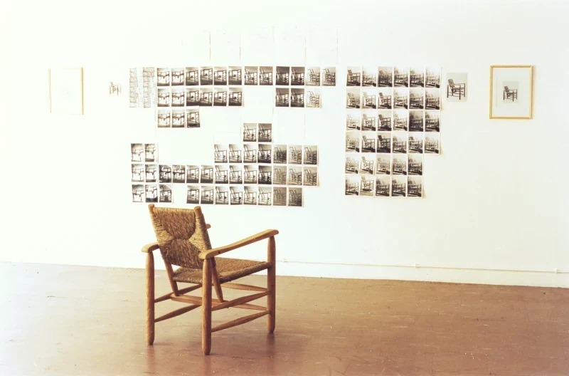 Une vue complète de l'installation : un fauteuil paillé fait face à des documents muraux qui racontent sa fabrication.